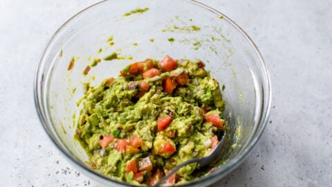 Mashed avocado and tomatoes in a bowl