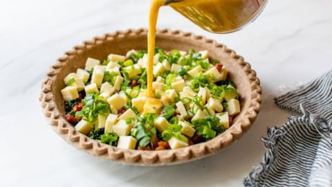pouring the egg and milk custard into easy quiche