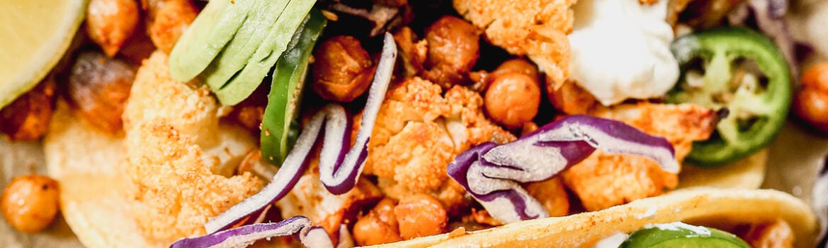 Crispy Cauliflower Tacos with chickpeas topped with avocado, jalapeno, and red cabbage