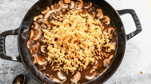 egg noodles added to a pan for beef stroganoff