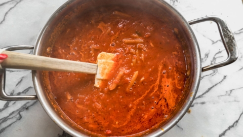 stirring marinara sauce and pasta in pot