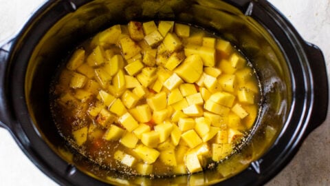 cubed potatoes, herbs, carrots, and chicken broth in a slow cooker